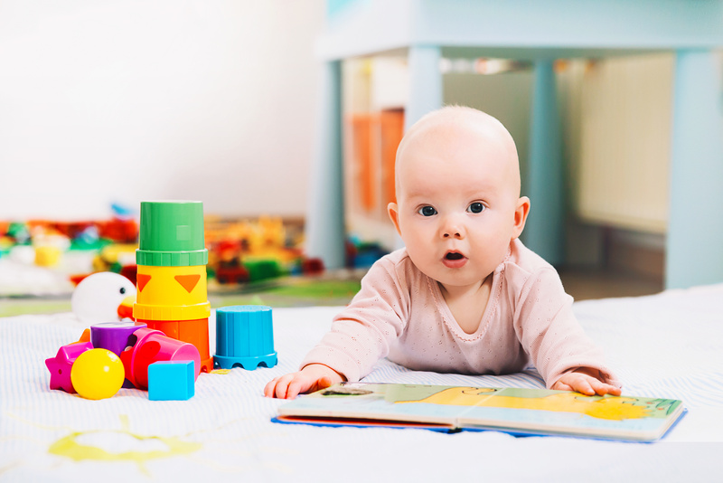 Adorable 6 months old baby looking and reading a book.